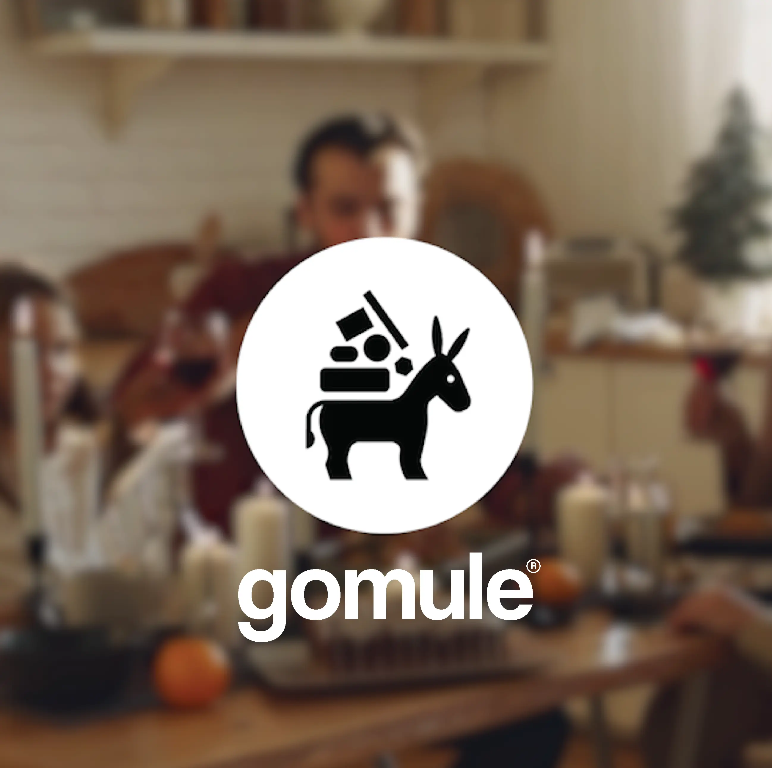 Logo for GoMule med en slørret baggrund af en familie omkring spisebordet.